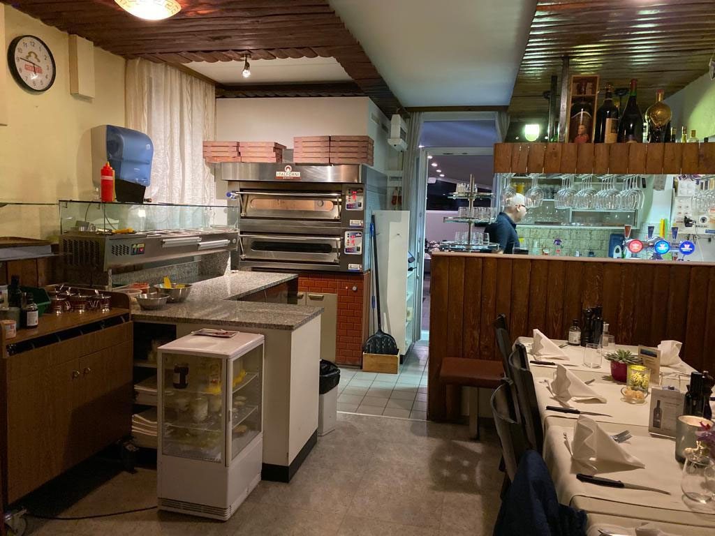 Blick von der Küche in den Gastraum, links der Ofen, rechts die Theke