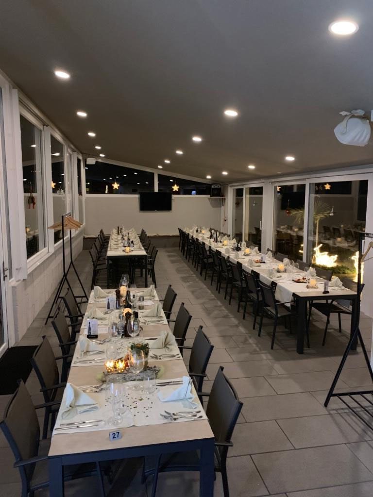 Der Saal mit langen Tischreihen, für eine Gesellschaft eingedeckt, dahinter die Fensterfront